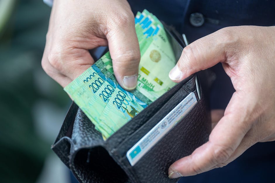 Person handling Kazakhstani tenge banknotes from a wallet, close-up view.